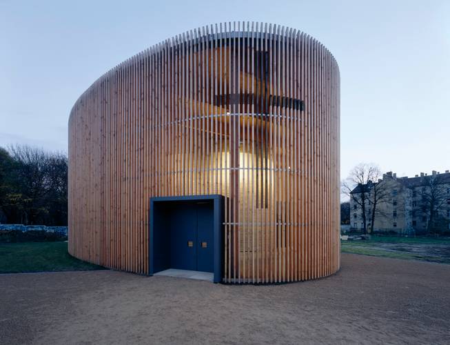 Reitermann / Sassenroth, Kapelle der Versöhnung, 1996–2000 – Außenansicht der Kapelle der Versöhnung in Berlin. Die Architektur der Kapelle ist schlicht und besteht aus einer hölzernen Außenkonstruktion mit blauer Eingangstür und einem Lehmbau im Inneren.