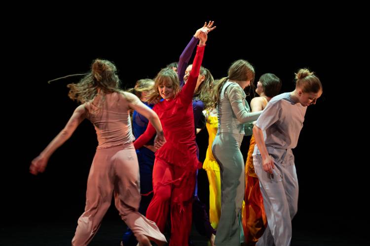 find no words to say – Personengruppe in farbenfroher Kleidung tanzt dynamisch auf dunkler Bühne.