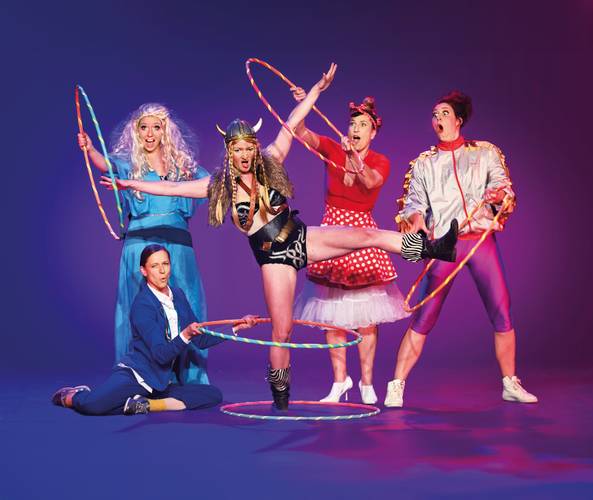 Barbaren Barbies: A wild women circus – Fünf Personen mit Hula-Hoop-Reifen posieren bunt gekleidet vor lila Hintergrund; eine trägt Wikingerhelm, eine andere ein blaues Kleid.