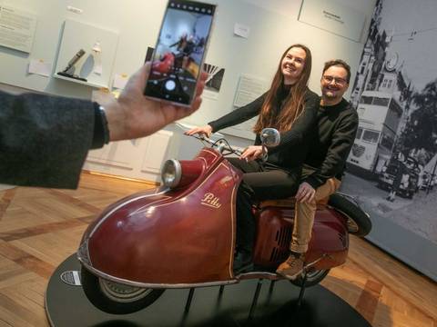 Der Motorroller „Pitty“ vermittelt beim Probesitzen einen sattelfesten Eindruck vom Berliner Straßenverkehr in den 1950er Jahren. – Zwei Besucher:innen beim "Foto-Shooting" auf dem Motorroller.