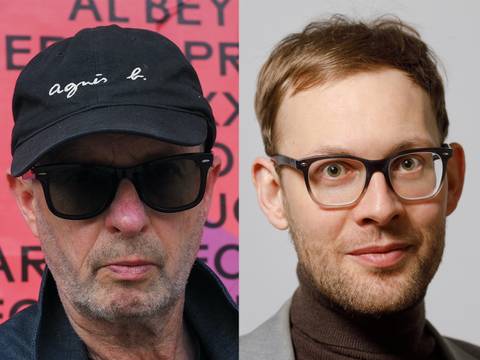  – Zwei Personen nebeneinander: links mit Sonnenbrille und Mütze mit Schriftzug agnès b., rechts mit Brille und hellem Hintergrund.