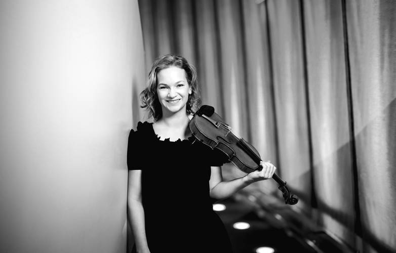 Die Violinistin Hilary Hahn – Eine Geigerin steht an der Wand gelehnt und schaut in die Kamera.