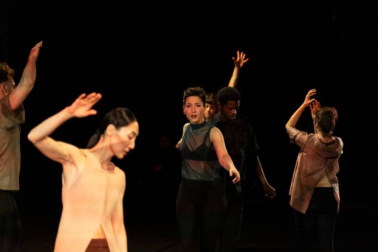 for the time being 1 – Mehrere Performer*innen, tanzend vor schwarzem Hintergrund