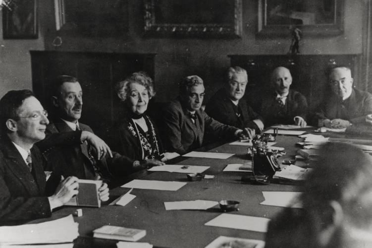 Sitzung der Sektion für Dichtkunst, 1929: Alfred Döblin, Thomas Mann, Ricarda Huch, Bernhard Kellermann, Hermann Stehr, Alfred Mombert, Eduard Stucken (v.l.n.r.) – Personengruppe um einen Tisch; sieben Erwachsene in Anzug; Papiere und Schreibmaschine auf dem Tisch; Schwarzweißfoto.