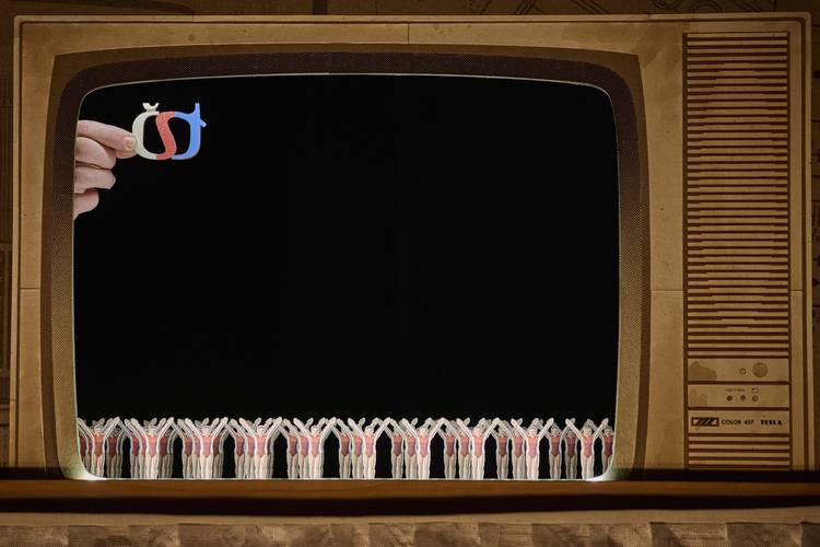 Loops & Hoops – Eine Hand hält die Buchstaben č, š, t über einem alten Fernseher. Unten stehen Figuren mit erhobenen Armen.