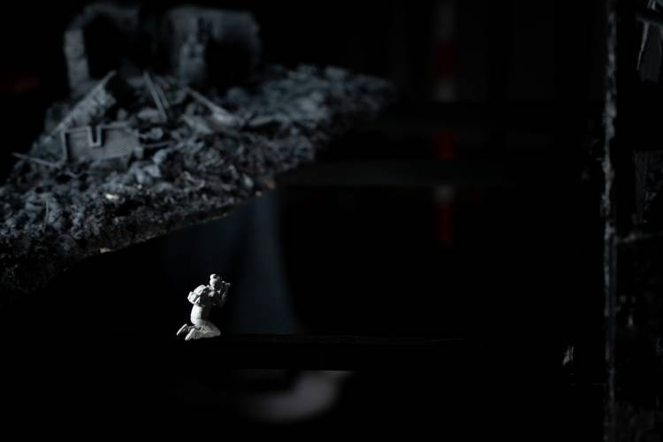 Transport: Frontline – Kleine Figur auf dunkler Fläche; im Hintergrund Trümmerlandschaft mit Ruinen und Schutt.