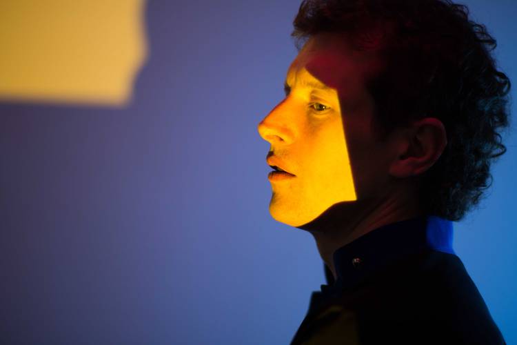 © Edith Buttingsrud Pedersen – Person im Profil, von gelbem Licht beleuchtet, blaue Wand im Hintergrund.