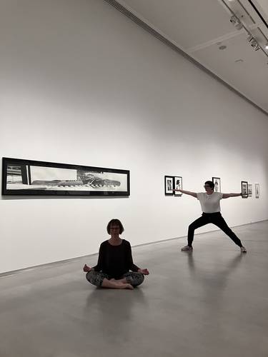Yoga in der Ausstellung „Marc Brandenburg. 20th Century Debris“ – Foto: Zwei Personen in Yoga-Kleidung sitzen beziehungsweise stehen in unterschiedlichen Yoga-Posen im Ausstellungsraum.