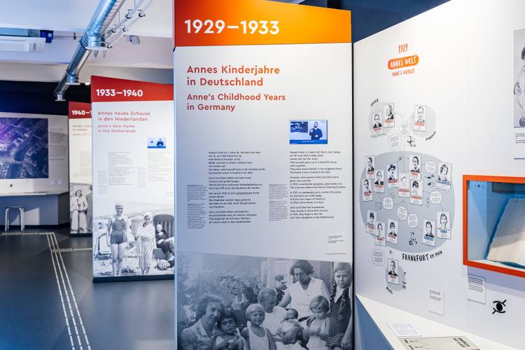 Blick in die Ausstellung – Mehrere Ausstellungswände mit Bild- und Textelementen sowie Videos in DGS