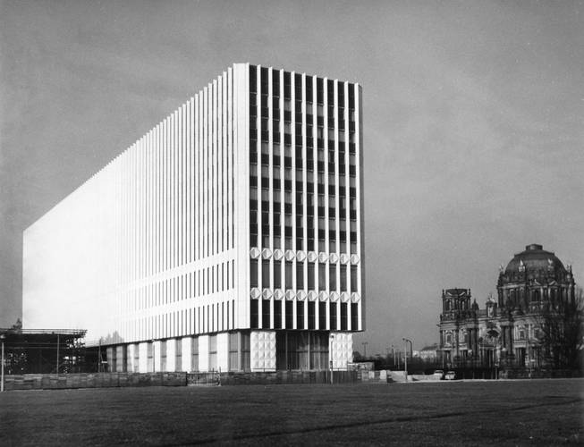 Lothar Willmann, Ministerium für Auswärtige Angelegenheiten der DDR, undatiert – Schwarz-weiß-Fotografie: Langes modernes Gebäude, daneben ein Dom, dunkel mit großer Kuppel.