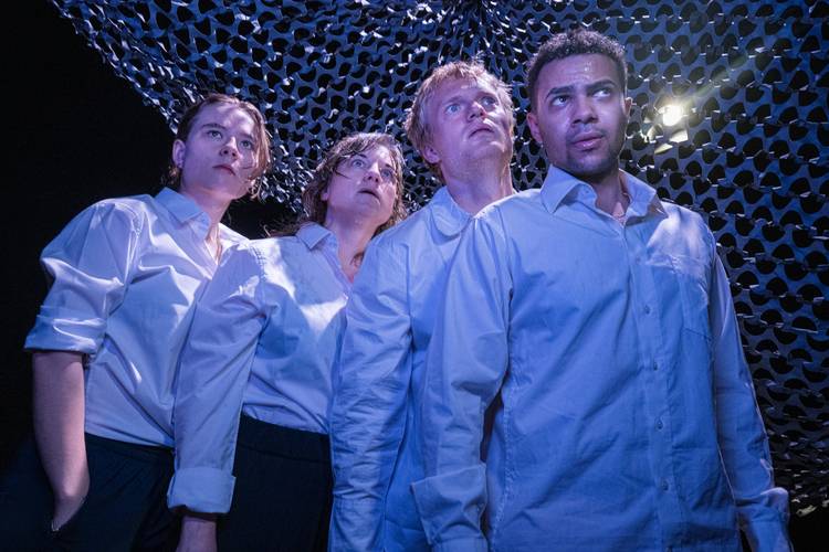 "Die Fische" am Theater Strahl – Vier Personen in weißen Hemden blicken nach oben. Der Hintergrund ist von einem dunkel gemusterten Stoff bedeckt. Licht von oben rechts.
