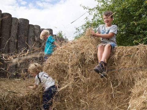 An der Dorfpalisade laden Haufen von Heuballen zum Austoben ein