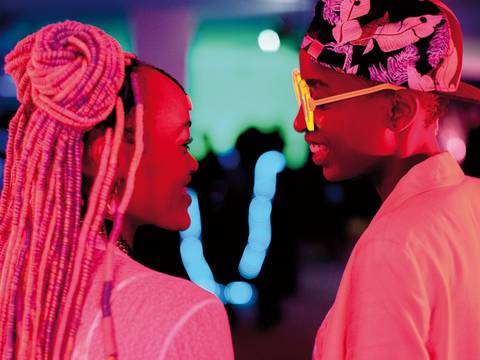 Show image caption ›Rafiki‹, Kenia 2018, Regie: Wanuri Kahiu, Bild: Salzgeber – Zwei Personen, die sich ansehen, in pinkem Licht.