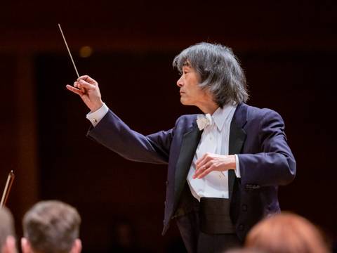 Kent Nagano – Person in Frack dirigiert mit Taktstock; Publikum im Vordergrund unscharf.
