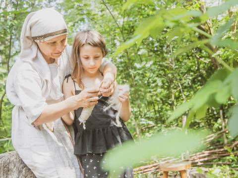 In Handarbeit entstehen aus Fasern Fäden. – Eine Frau zeigt einem Mädchen wie in Handarbeit aus Fasern Fäden entstehen