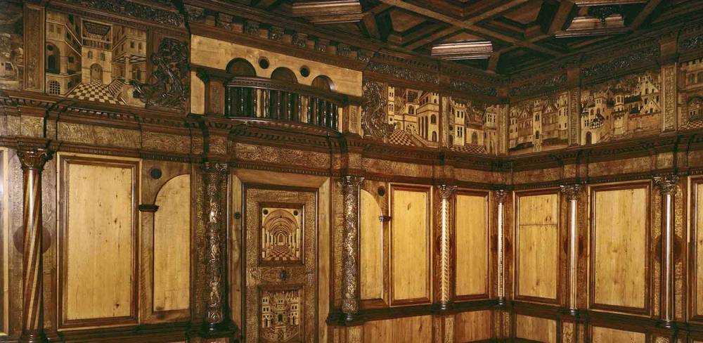 Vertäfelung aus der Prunkstube in Schloss Haldenstein bei Chur, Detail, Meister E.S. (?), Graubünden, um 1548 – Renaissance-Holzvertäfelung mit detailreichen Intarsien von Stadtszenen und Architektur in einem reich dekorierten Raum mit gewölbten Decken und Säulen.