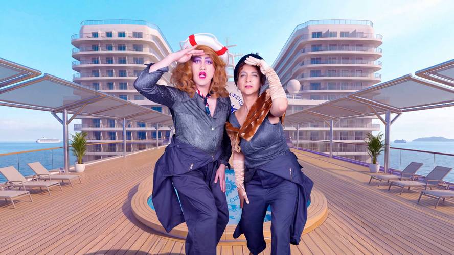 Zwei Personen auf einem Kreuzfahrtschiffdeck, posierend mit Hand an Stirn, tragen blaue Outfits und maritime Accessoires, im Hintergrund modernes Schiff.