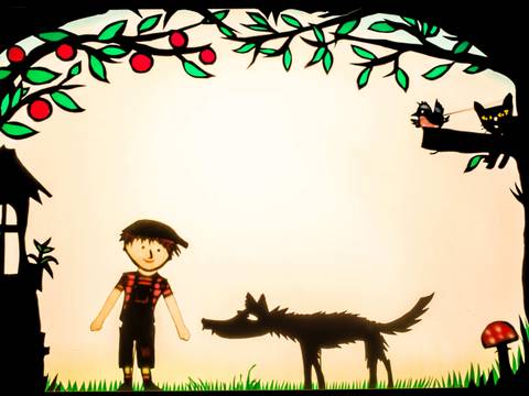 Theater Scuraluna mit dem farbigen Schattenspiel „Peter und der Wolf“ – Schattentheater mit Kind, Wolf, Haus, Vogel und Katze auf Baum, Äpfel hängen in Ästen, Gras und Pilz im Vordergrund.